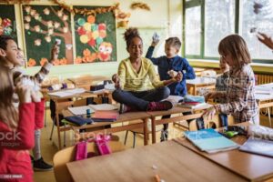 Fille afro-américaine méditant autour de ses camarades de classe ludiques lors d'une pause en classe.