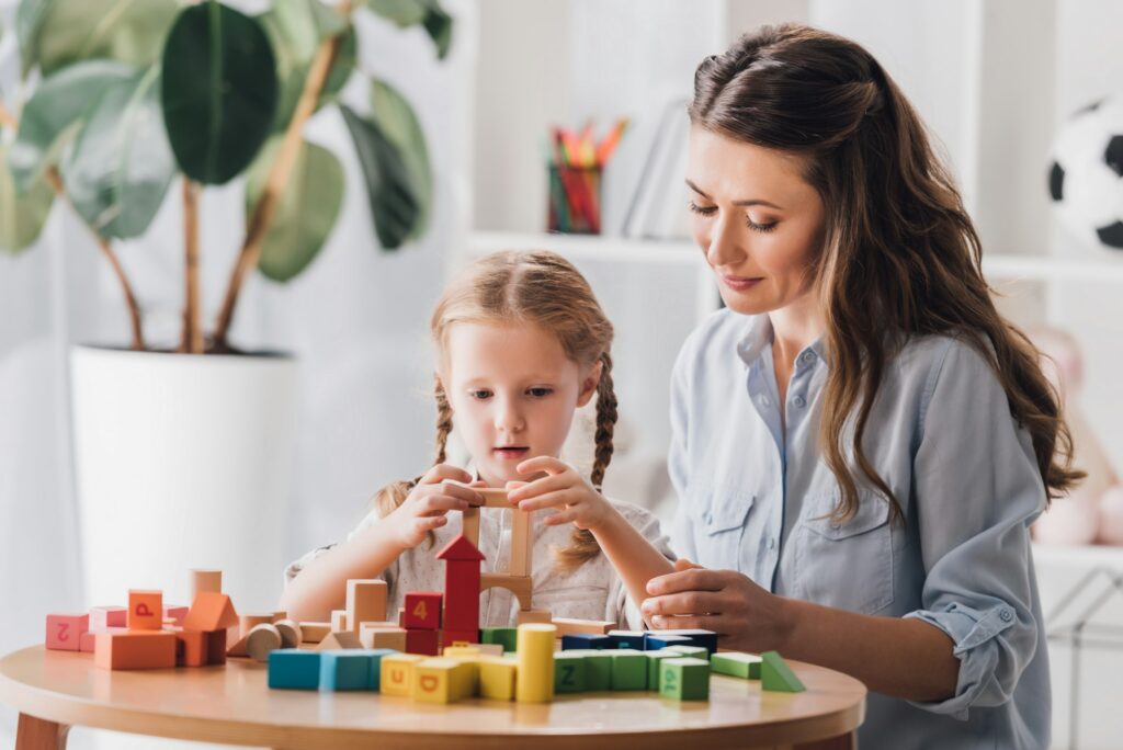 sophrologue jouant des blocs avec un petit enfant atteint du syndrome autistique