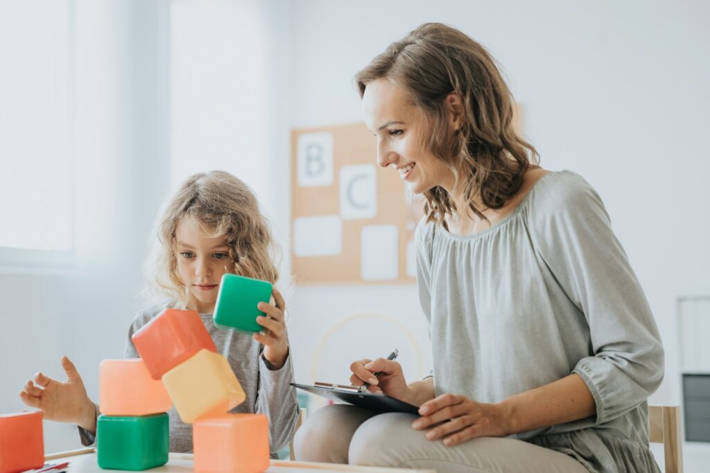 sophrologue jouant des blocs avec une petite fille atteint du syndrome autistique